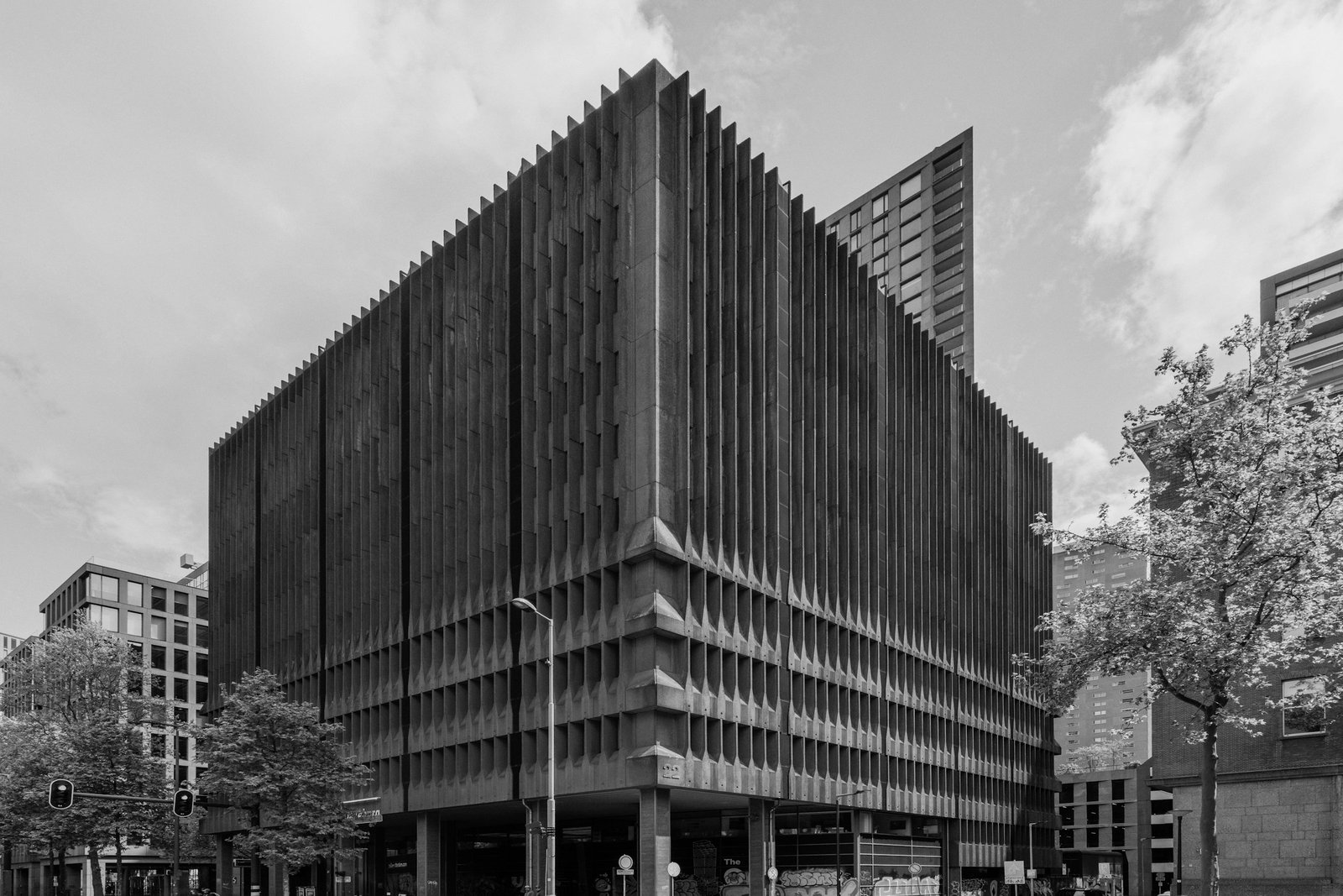 Esquina de un edificio brutalista de concreto con aletas verticales, en blanco y negro.